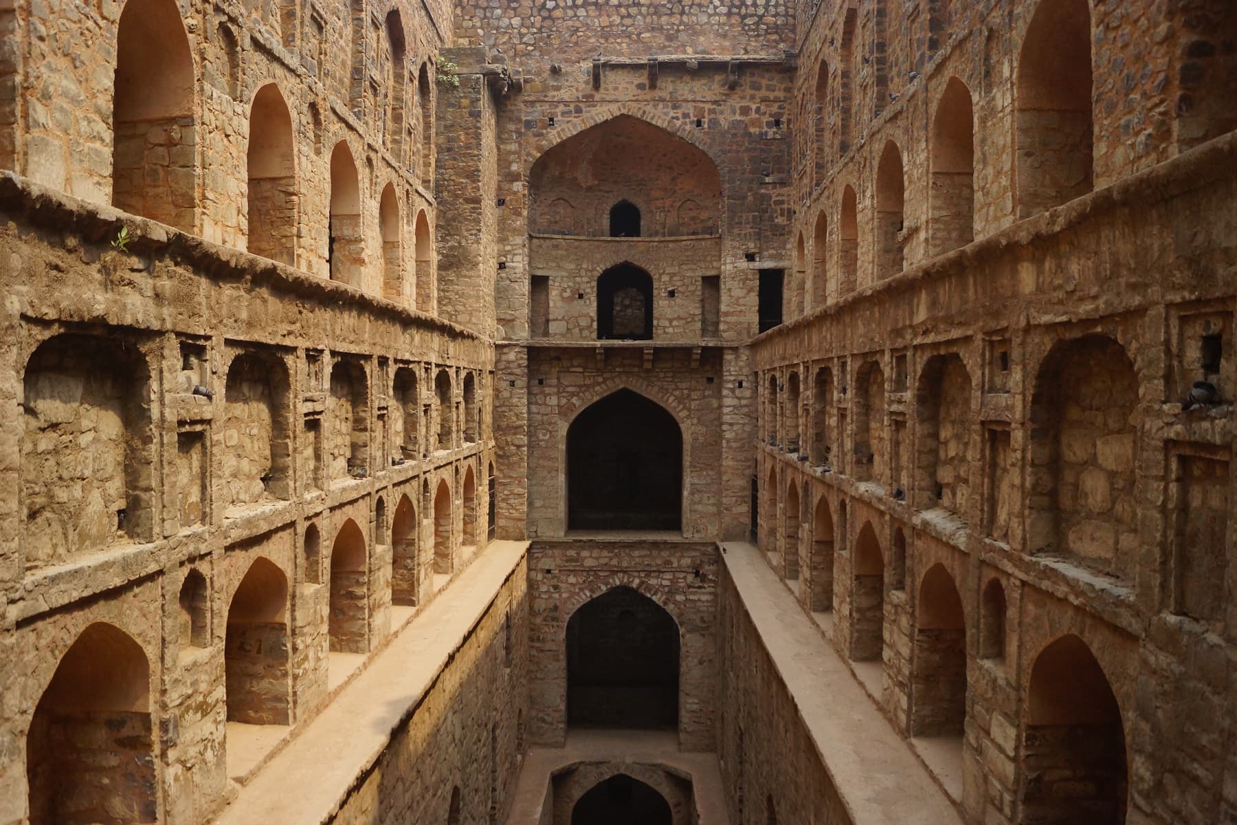 Agrasen ki Baoli in central Delhi: tiers of arched stone galleries descending steeply to the dry floor of a medieval stepwell.