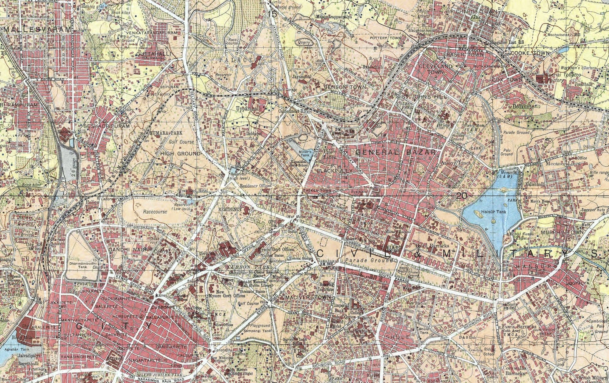 A detail of the Survey of India's Bangalore Guide Map, 1938 edition: dense streets of the old city in red, railway lines, and tanks shaded blue, including the large tank at the right edge.